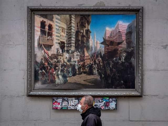 A man wearing a face mask walks past a painting in central Moscow - Read Photos